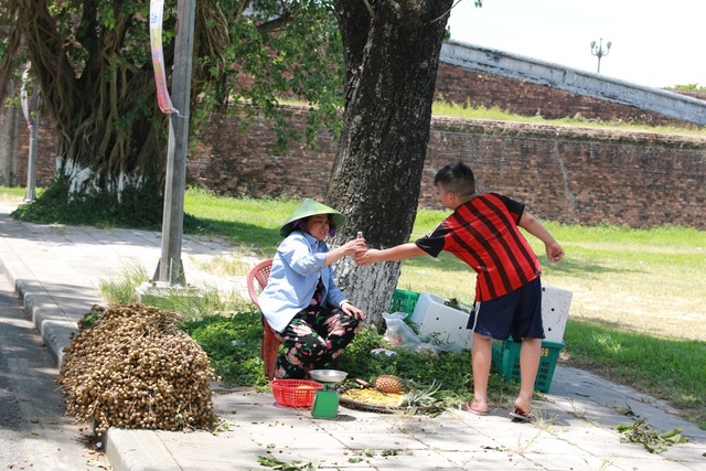 Huế “oằn mình” dưới nắng nóng 40 độ C - 4 Con trai tiếp nước cho mẹ bán hàng trong cái nắng như đổ lửa
