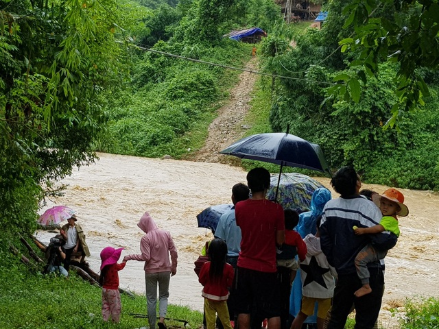 Hơn 300 người dân Khơ Mú bị cô lập trong nước lũ - 2 Hơn 300 người dân tại đây bị mắc kẹt do nước lũ lên cao. Trường học, diện tích đất sản xuất của bản đều ở phía bên kia khe Nậm Hỷ. Chỉ cách đường quốc lộ một con khe, thế nhưng, bà con dân bản không thể qua lại, đành bất lực đứng nhìn dòng nước hung dữ.