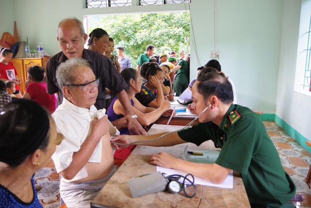 Hối hả dọn bùn sau lũ dữ - 17 Quân y BĐBP hướng dẫn người dân cách sử dụng thuốc chữa bệnh. (Ảnh: Lê Thạch)