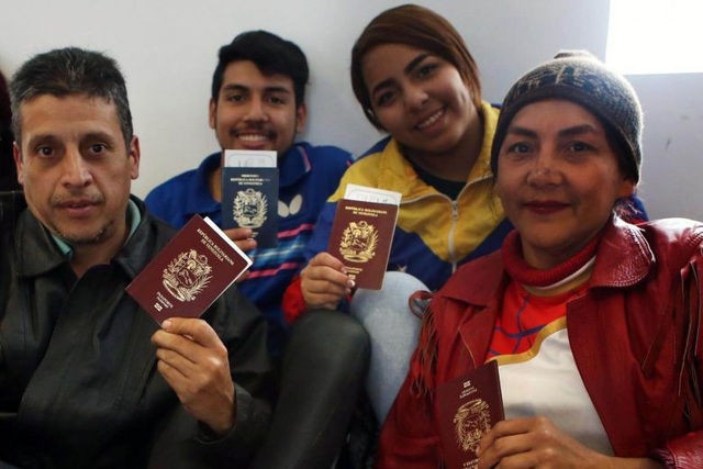 Sinh kế tại nước ngoài khốn đốn, người tị nạn Venezuela theo chính phủ hồi hương - 1 Những người Venezuela tị nạn cầm trên tay hộ chiếu và vé máy bay chuẩn bị hồi hương (Ảnh: AFP)