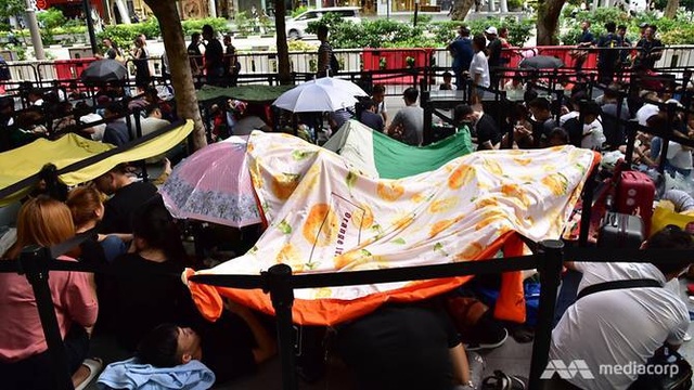 Chuyện người Việt xuất ngoại, xếp hàng chờ mua iPhone lên báo nước ngoài - 3 Nhiều người ngồi xếp hàng bất chấp trời nóng và cơn mưa to đổ xuống (Ảnh: Channel NewsAsia)