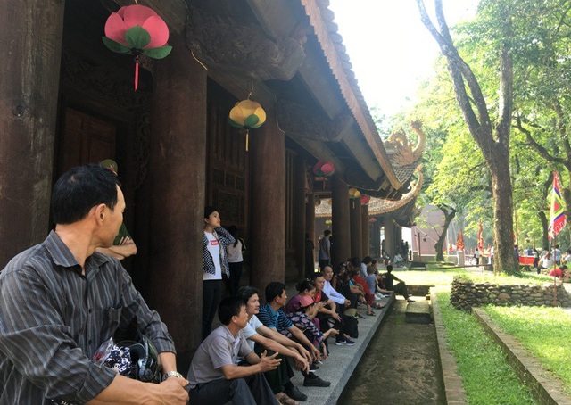 Nhiều người dân, du khách ngồi nghỉ ngơi bên hiên của Chính điện Lam Kinh.