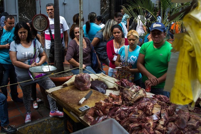 Venezuela siêu lạm phát 440.000%, tiền mất hoàn toàn giá trị - 1 Người dân đứng xếp hàng để mua thịt không rõ nguồn gốc trên đường phố ở thủ đô Caracas. (Nguồn: Wil Riera / Bloomberg)