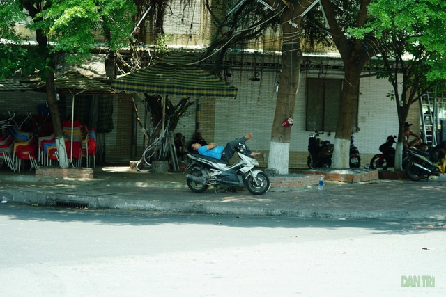 Một người dân phải nằm ngay trên yên xe để ngủ khi quán cà phê phía sau không hoạt động.