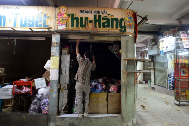 Ông Hoàng (56 tuổi) đã kinh doanh ở chợ hơn 20 năm nay đang kéo cửa đóng quầy đi gọi người dọn hàng phụ.
