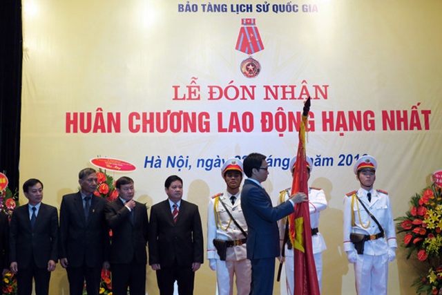 Bảo tàng Lịch sử Quốc gia đón nhận Huân chương Lao động hạng Nhất - 1 Phó Thủ tướng Chính phủ Vũ Đức Đam gắn Huân chương Lao động hạng Nhất lên lá cờ truyền thống của Bảo tàng Lịch sử Quốc gia. Ảnh: Hoàng Nguyên.