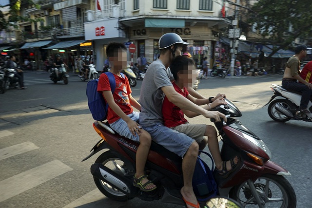 Nguy hiểm rình rập trẻ nhỏ không đội mũ bảo hiểm trên xe máy - 3
Hiện tượng chở hai, ba trẻ nhỏ không đội mũ bảo hiểm được nhìn thấy nhiều hơn tại những quận trung tâm thành phố như Hoàn Kiếm, Ba Đình. Các trường học khu vực này thường ở len lỏi trong các con phố cổ, khoảng cách đên trường gần khiến nhiều phụ huynh lơ là việc đội mũ bảo hiểm cho con em mình.