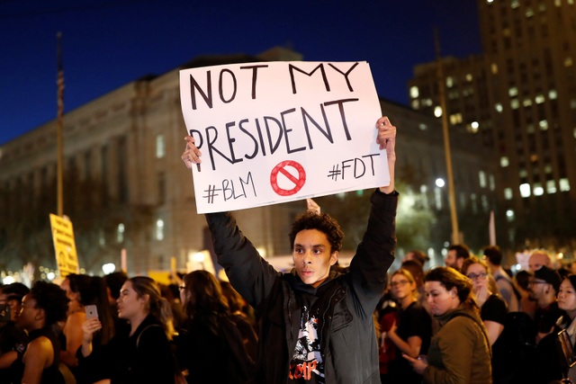 
Các cuộc biểu tình diễn ra tại nhiều bang ở Mỹ sau khi ông Donald Trump đọc diễn văn mừng chiến thắng vào sáng ngày 9/11. Trong ảnh: Người biểu tình ở San Francisco, bang California giơ tấm biển ghi dòng chữ “(Trump) không phải tổng thống của tôi”.
