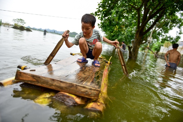Gà vẫn ở trong nhà dân ngoại thành Hà Nội sau một tuần ngập lũ - 13
Bé trai đi bè trong xóm.