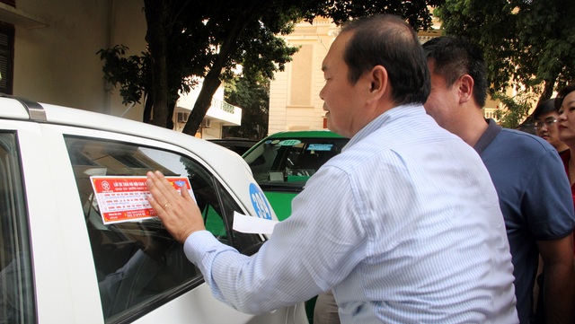 Hà Nội dán đề can tuyên truyền luật giao thông cho gần 20.000 xe taxi - 1 Ông Hà Huy Quang - Phó Giám đốc Sở GTVT Hà Nội tự tay dán đề can cho xe taxi.