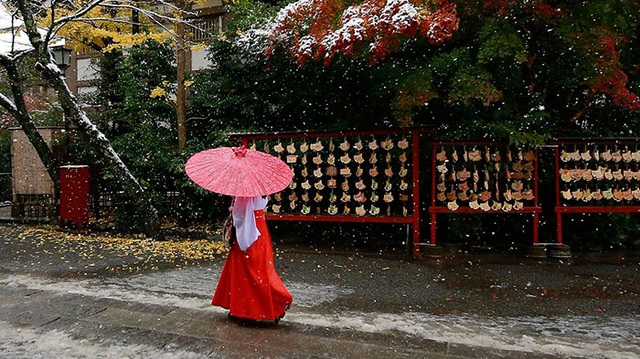 Thiếu nữ trong trang phục truyền thống đi dưới làn tuyết mờ ảo