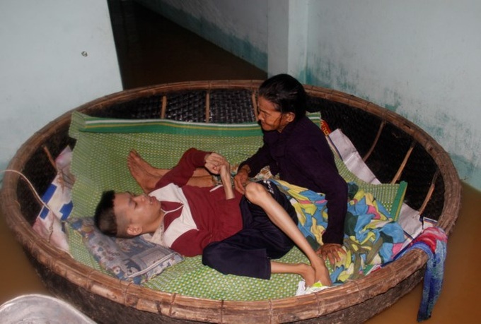 Elderly mother looks after Agent Orange son in flood - 1