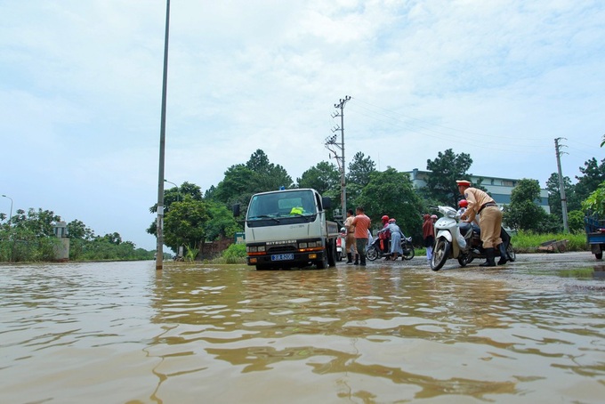 Hanoi traffic police help people on flooded road - 4