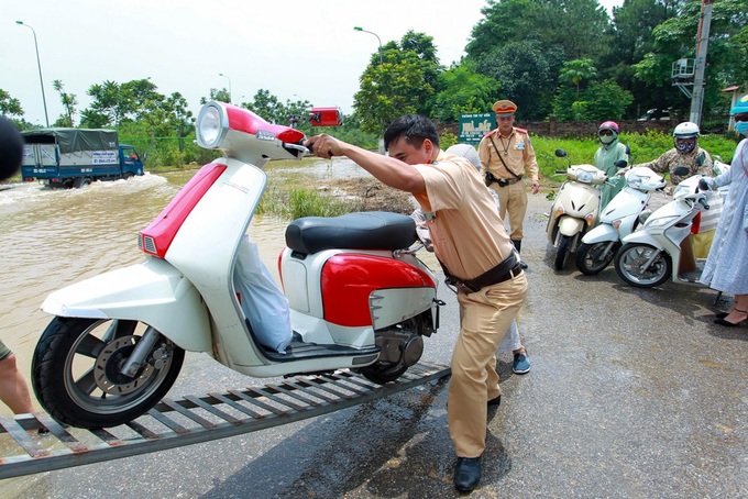 Hanoi traffic police help people on flooded road - 2