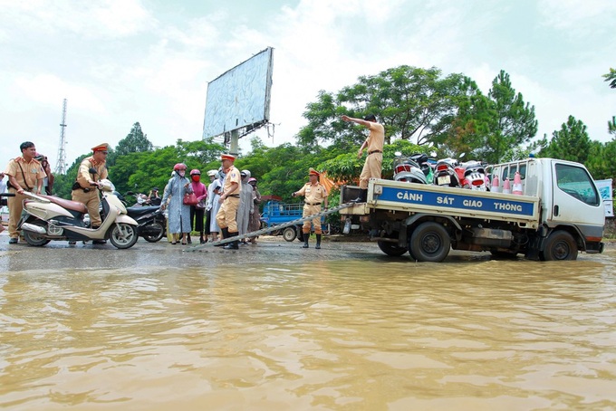 Hanoi traffic police help people on flooded road - 1