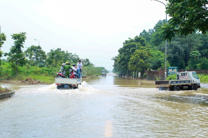 Hanoi traffic police help people on flooded road - 5