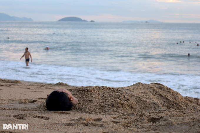 Nha Trang residents bury themselves in sand at dawn - 3