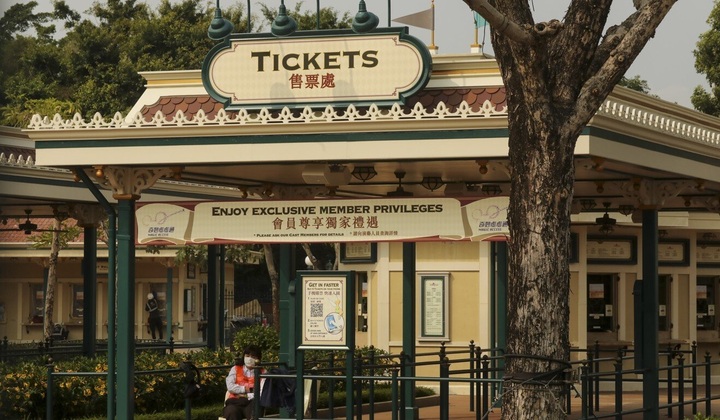 An employee stands at the closed gates of Hong Kong Disneyland which has been shut because of the coronavirus. Photo: K.Y. Cheng