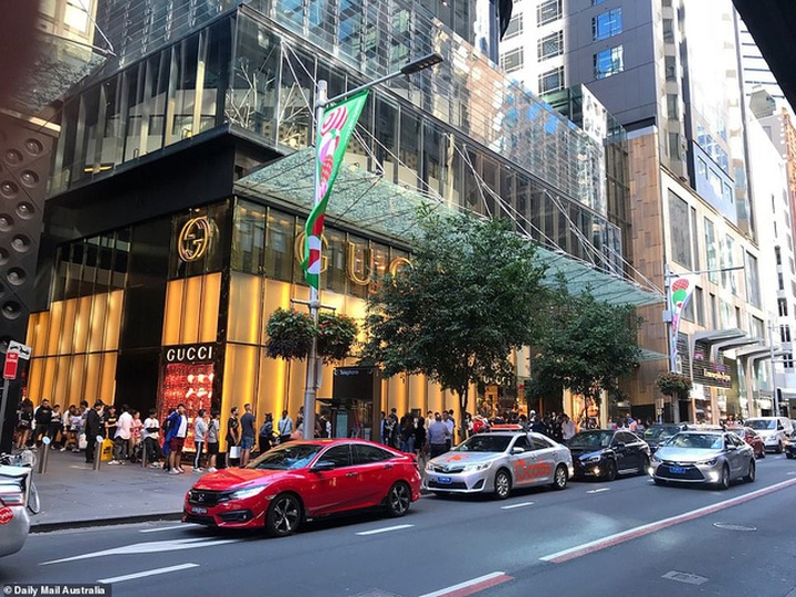 Nhân viên của thương hiệu thời trang Gucci phát nước uống cho những khách hàng đang kiên nhẫn chờ đợi trước cửa hiệu của hãng tại Sydney, Australia. (Ảnh: Dailymail)