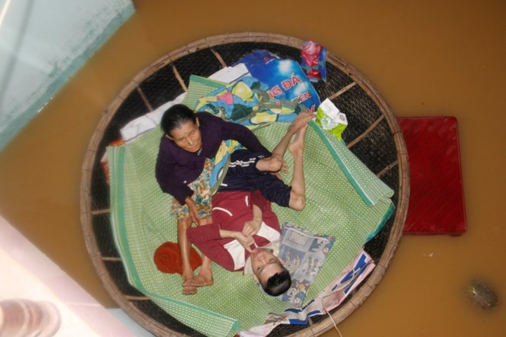 Elderly mother looks after Agent Orange son in flood - 3