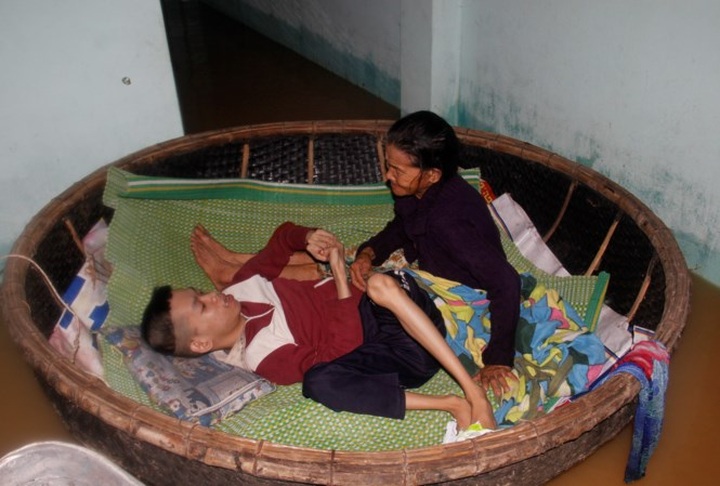 Elderly mother looks after Agent Orange son in flood - 1