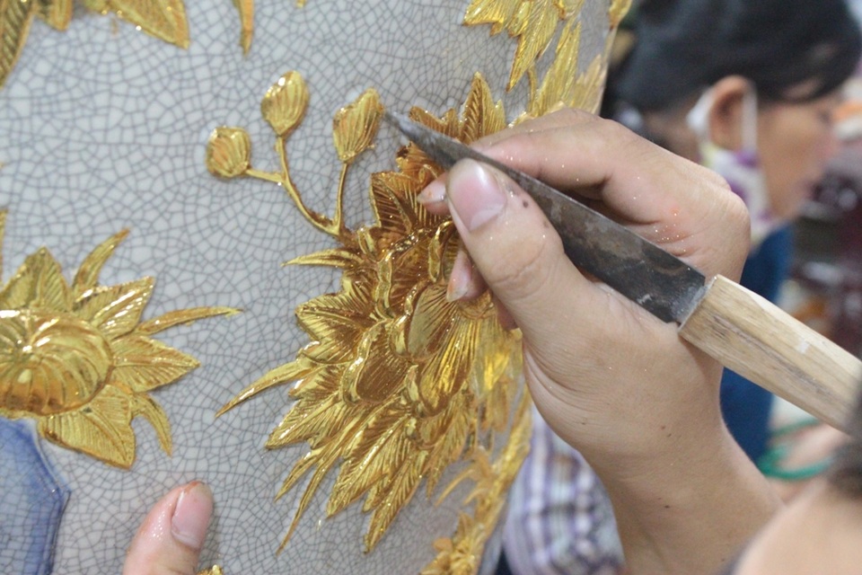 Cận cảnh bộ đồ gốm men cổ dát vàng “độc nhất vô nhị” tại Việt Nam - 15 Nói về công đoạn dát vàng, cô Lê Thị Hậu – nghệ nhân dát vàng làng Kiêu Kỵ cho biết: “Vàng vốn rất mỏng nên chúng tôi phải kì công dát từng chút một. Trước hết, phải đợi khô sơn lót rồi mới có thể bắt tay vào làm. Tính ra trung bình, 1 bộ gốm dát vàng cần sử dụng khoảng hơn 3 cây vàng mới hoàn thiện”.