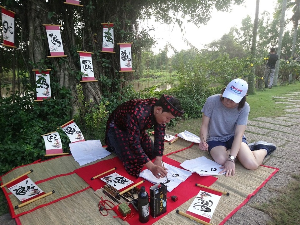 Du khách thích thú trải nghiệm Tết Việt - 4 Một nữ du khách thử tập viết chữ thư pháp truyền thống