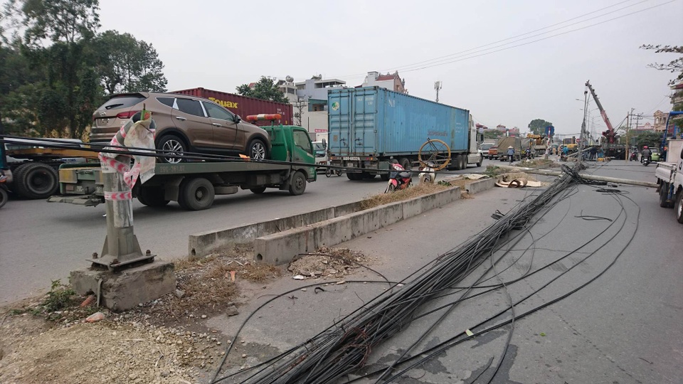 
Cột điện đổ rạp xuống đường kéo theo búi dây điện lùng nhùng. Cột đèn chiếu sáng cũng gãy gập, đã được lực lượng chức năng cắt sát gốc.
