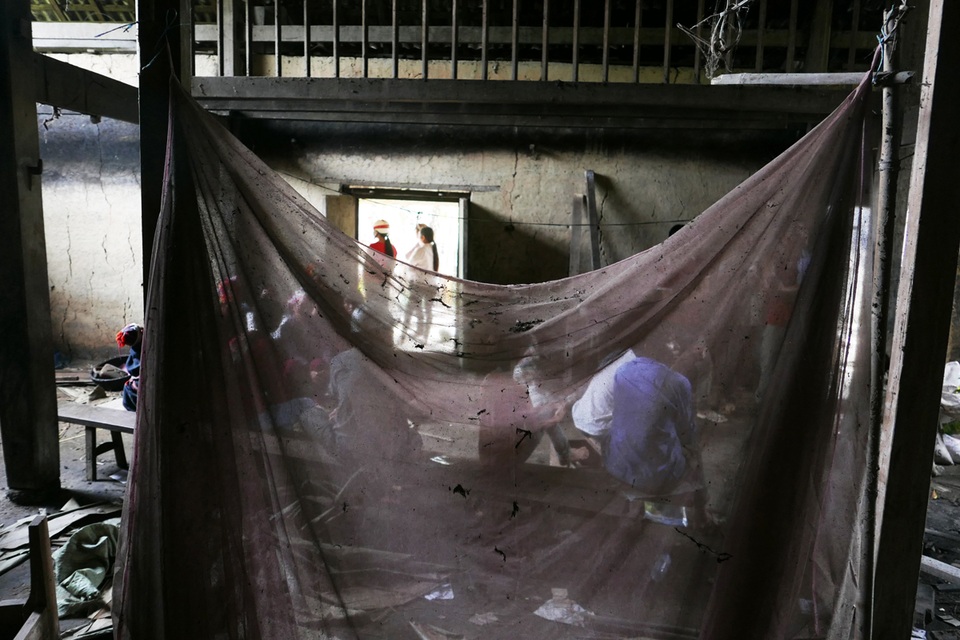 
Tấm màn mắc dở vẫn buông thõng giữa nhà.
