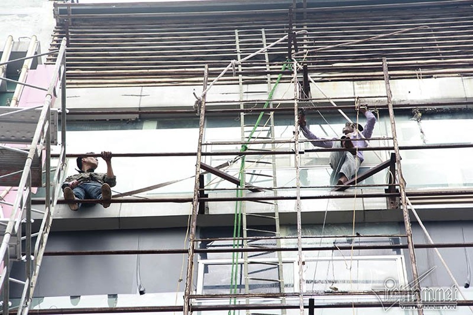 Công nhân được thuê để tháo những tấm biển quảng cáo khủng xuống (ảnh chụp trên đường Trần Thái Tông)