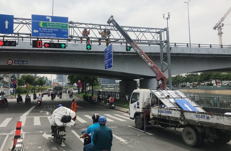 Lắp thêm biển chỉ đường bằng tiếng Anh trên đại lộ Sài Gòn - 3 Các công nhân đang thi công thay thế, lắp bổ sung biển chỉ đường bằng tiếng Anh tại giao lộ Võ Văn Kiệt - Nguyễn Thái Học, sáng 20/5.