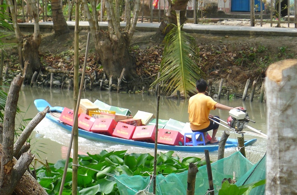 Về miền Tây đừng quên thưởng thức cá lóc đồng nướng rơm - 12 Một chủ tiệm tạp hóa dùng ghe tam bản chở bia... phục vụ ngày tết