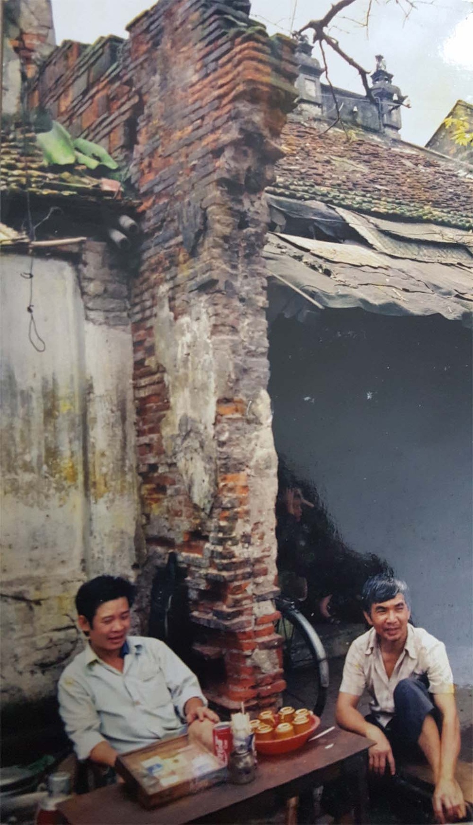 
Một bức ảnh màu chụp 2 người đàn ông ngồi tán gẫu trên vỉa hè ở ngã 3 Hàng Bè năm 1982
