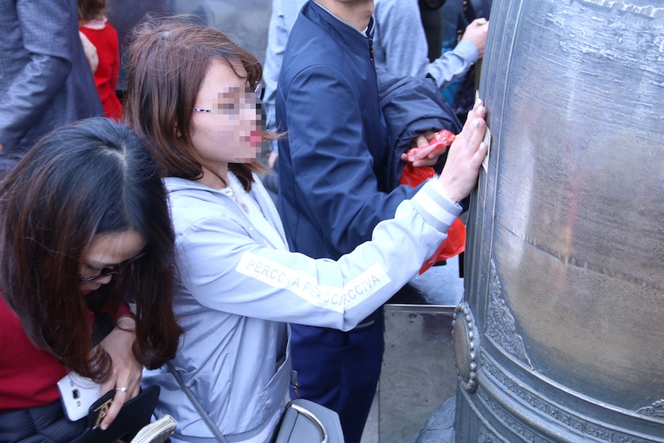 
Nhiều bạn trẻ dùng tiền lẻ xoa lên mặt chuông ở chùa Đồng để lấy may, gây hình ảnh phản cảm.
