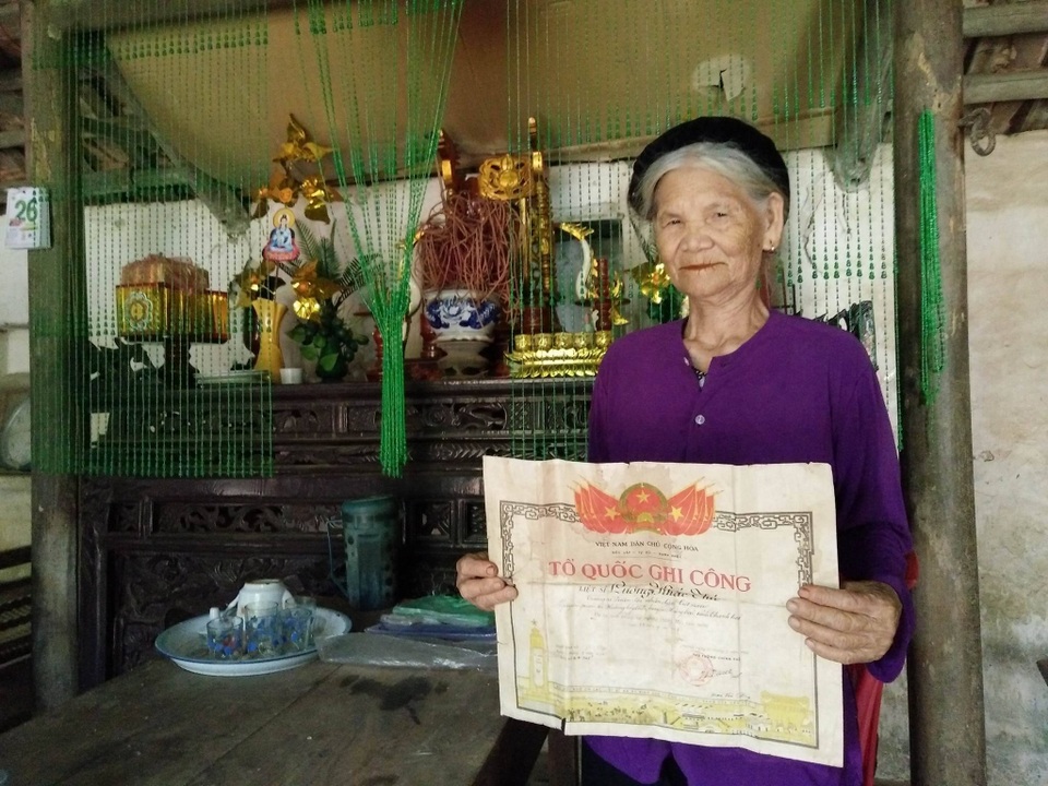Vợ liệt sĩ mong có căn nhà mưa không dột, nắng không chói vào để thờ chồng - 1 Cụ Miêng bên tấm bằng Tổ quốc ghi công của liệt sỹ Lương Khắc Thứ đã bị nước mưa dột vào nhà làm nhòe nhoẹt, mốc ố