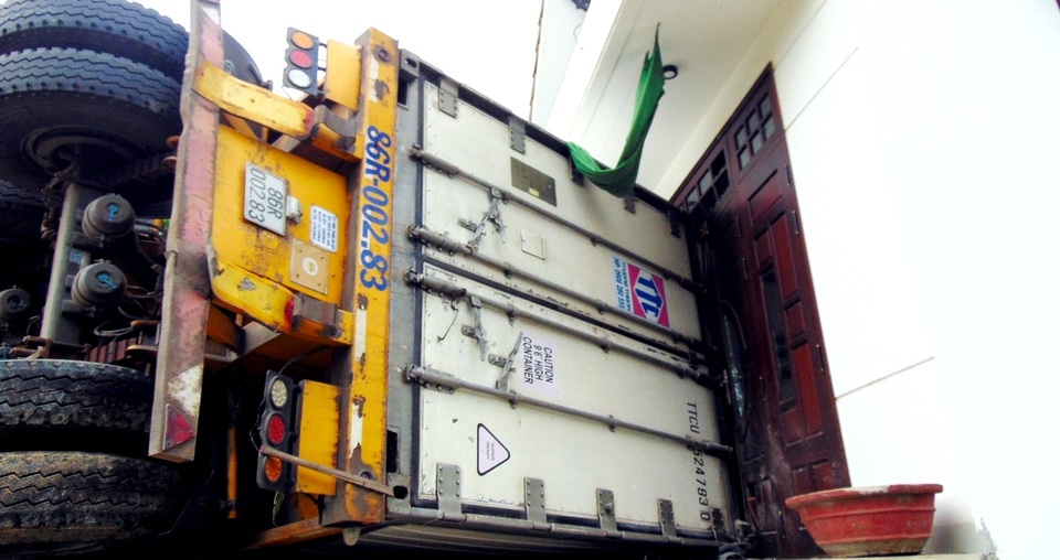 Xe "khủng" lật nghiêng sát nhà dân, 2 người bị thương nặng - 2 Một phần thân xe lao vào nhà dân làm cửa bị hư hỏng