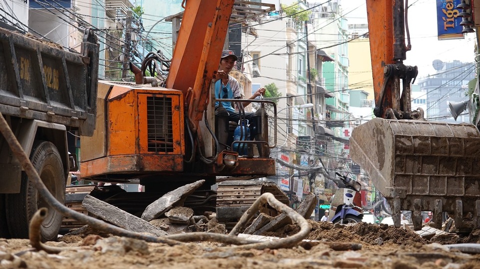 Tất bật “thay da” cho đường Bùi Viện trở thành phố đi bộ - 2 Máy xúc đang bốc dỡ bề mặt vỉa hè cũ.