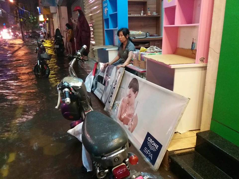 
Một chủ cửa hàng trên đường Tô Hiệu tìm cách ngăn không cho nước hắt vào số đồ gỗ
