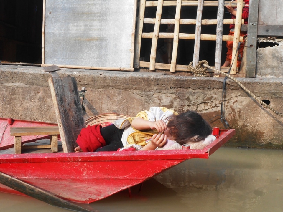 Một bé gái trong lúc đợi mẹ đánh cá đã ngủ ngay trên thuyền