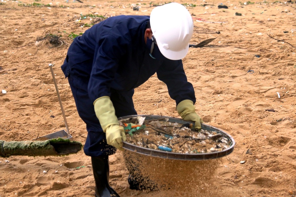 Sàng cát để thu gom dầu và rác thải tấp vào bờ biển - 1
Công nhân dùng sàng để sàng cát để thu gom dầu vón cục và rác