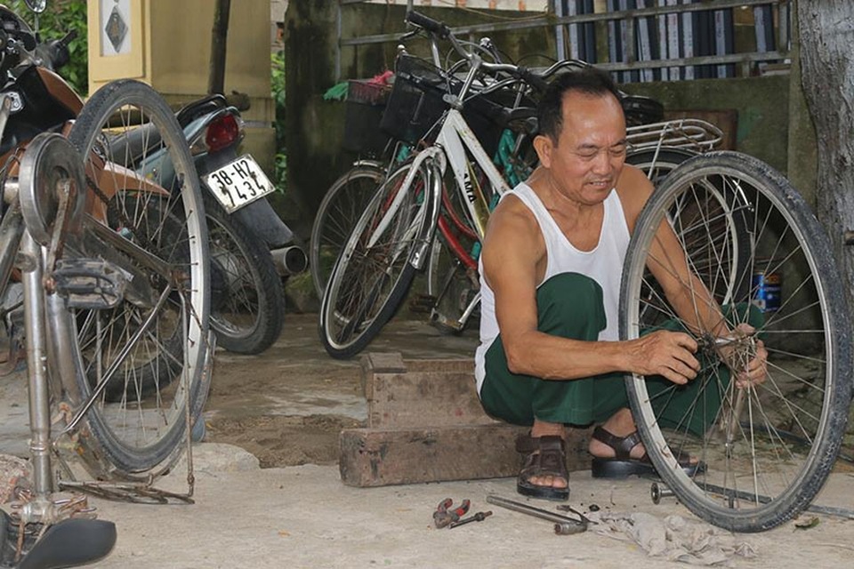 Gặp “ông bụt” của những học sinh nghèo - 2 Nhiều lúc đang ăn cơm nhưng ông Thực bỏ dỡ bữa ăn để sửa xe cho các em học sinh.