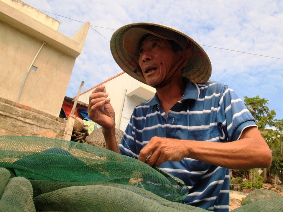 Ngư dân Huỳnh Công Chính đang tranh thủ vá lưới chuẩn bị cho chuyến biển sắp tới
