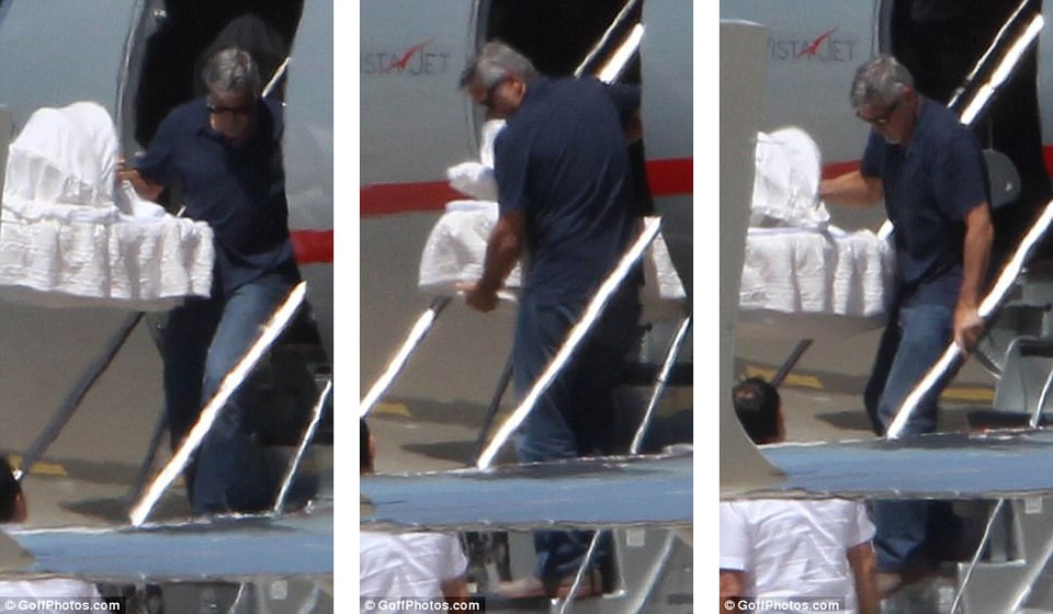 Nam tài tử rất cẩn thận khi di chuyển chiếc nôi có con nhỏ nằm trong từ trên máy bay xuống tới chiếc xe hơi chờ sẵn.