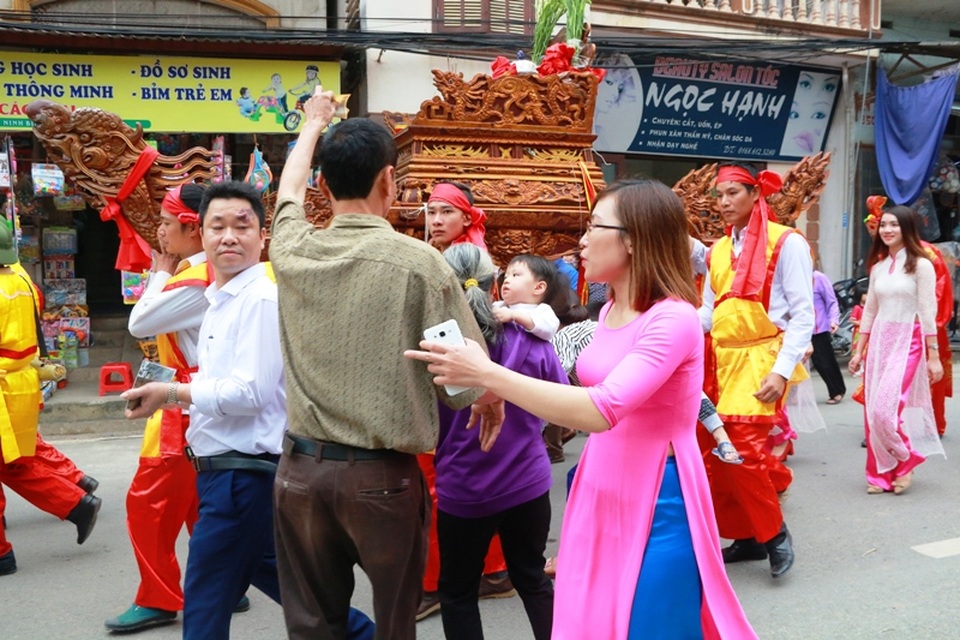 Thấy chiếc kiệu đến, một người đàn ông nhanh tay bỏ tiền lẻ lên trên kiệu. Quan niệm của người dân cố đô Hoa Lư, kiệu nước thiêng liêng nên bỏ tiền lên để cầu may mắn.