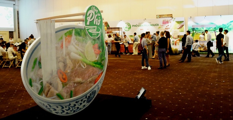 Thực khách thích thú “chạm tay” vào lịch sử của sợi phở - 6 Bên trong biểu tượng gồm có cụm chữ Ngày của Phở, hình cây lúa, đôi đũa, sợi phở, và nét cách điệu của bát (tô) sứ dùng để ăn phở