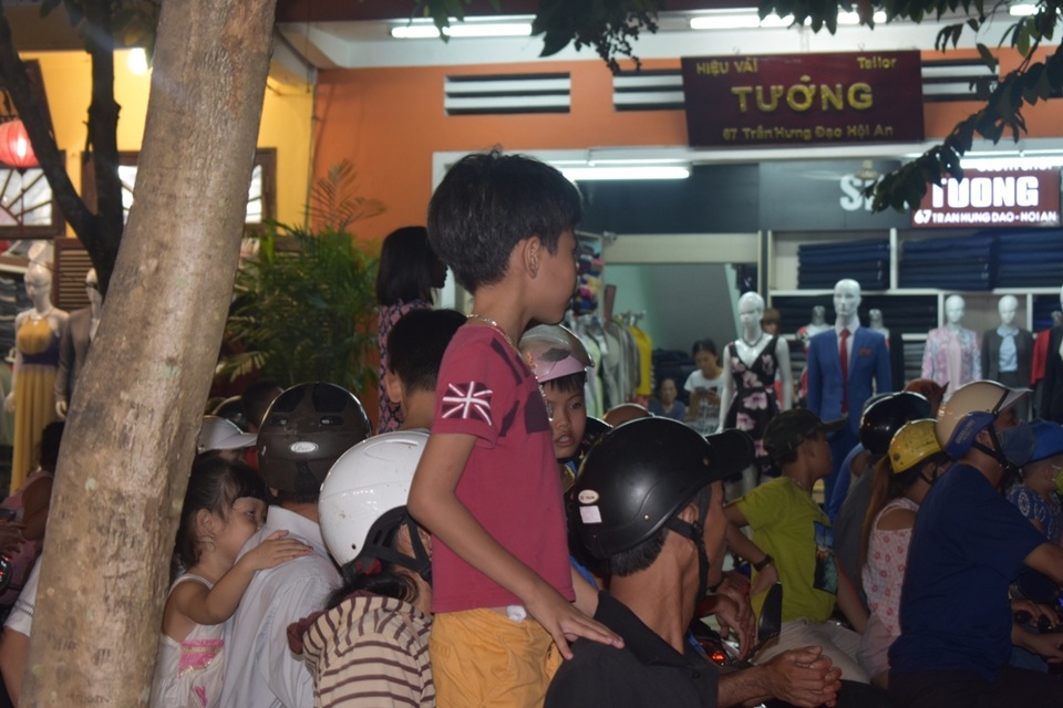Hàng ngàn người dân và du khách đội mưa xem múa lân - 5 Nhiều em nhỏ được cha mẹ cho đứng trên xe để xem dễ hơn