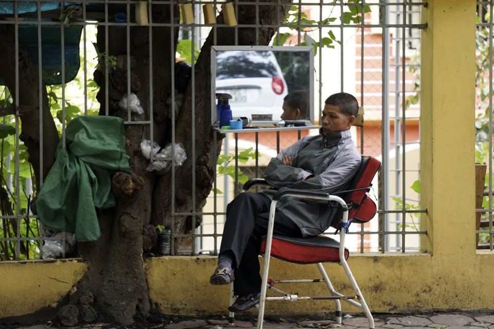 
Người cắt tóc ngồi co ro đợi khách.
