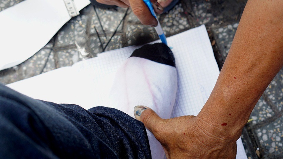 Nếu khách hàng có nhu cầu đóng mới, anh Văn có một chiêu lấy số đo bàn chân rất chất mà có lẽ chỉ ở đây mới có. Khách hàng đặt chân lên quyển sổ rồi anh lấy bút gò nét viền theo khuôn chân của khách