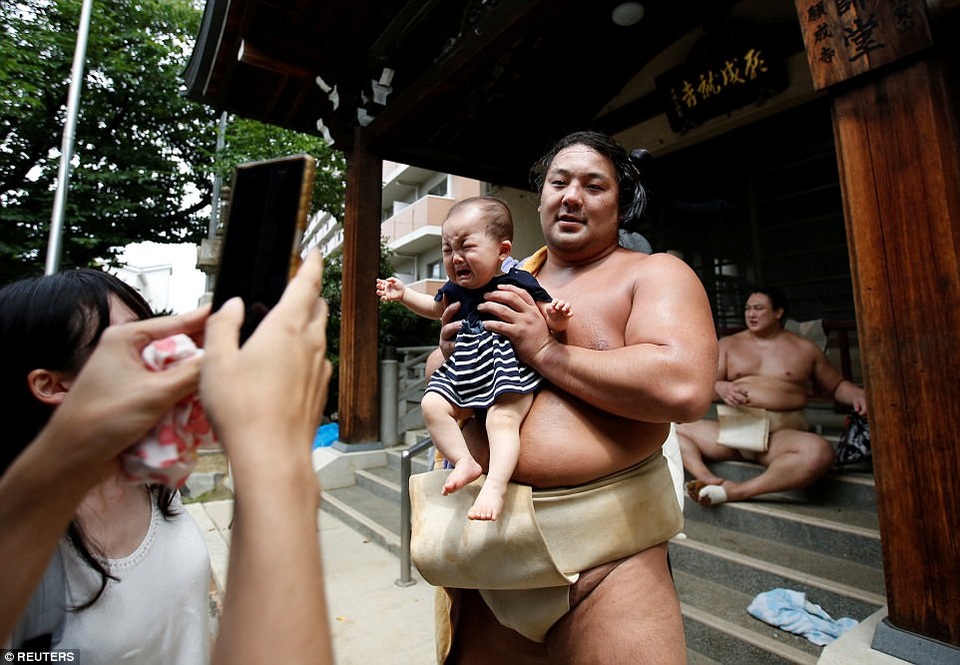 Vén màn bí mật về cuộc sống của những sumo Nhật Bản - 8
Đô vật Kyokutaisei chụp ảnh với trẻ em bên ngoài đền Ganjoji Yakushido. (Ảnh: Reuters)