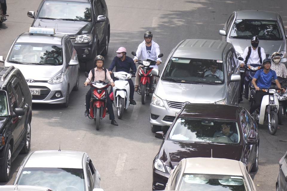 Nhiều người đỗ đèn đỏ phải núp tạm trong bóng mát của cây xanh dù cách xa vị trí đèn đỏ.